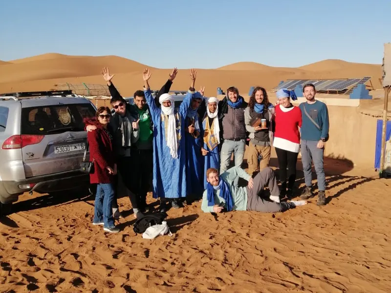 Groupe de voyageurs et Salah au campement, devant les dunes, avant le départ